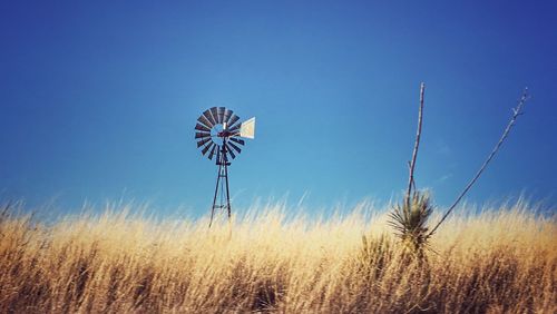 Low angle view of windmill on field against sky