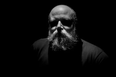 Close-up of bearded man against black background