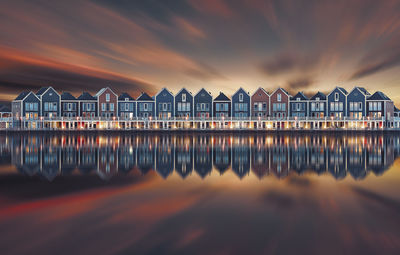 Houses by sea against sky during sunset