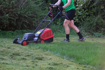 Low section of man mowing lawn