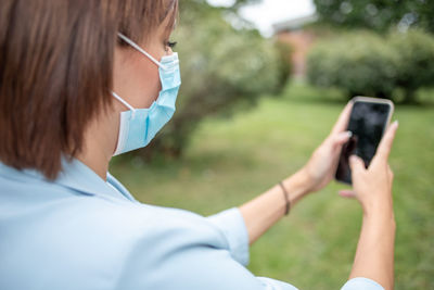 Rear view of woman photographing with mobile phone