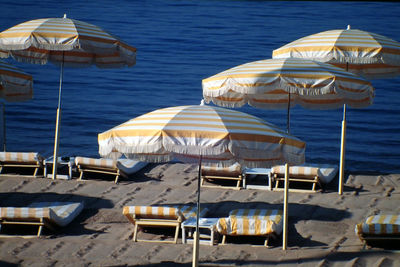 Lounge chairs by parasols at beach