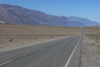 Road by mountains against sky