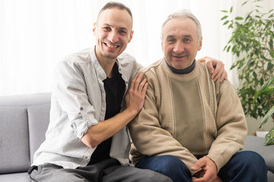 Portrait of smiling couple sitting on sofa at home