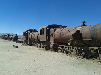Train on beach against clear blue sky