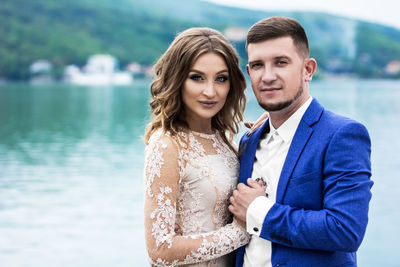 Portrait of couple standing against lake