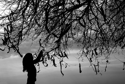 Silhouette man standing by tree against sky