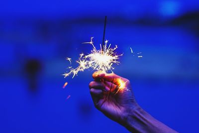 Close-up of hand holding illuminated sparkler at night