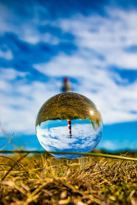 Close-up of crystal ball on field against sky