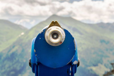 Close-up of coin-operated binoculars against mountains