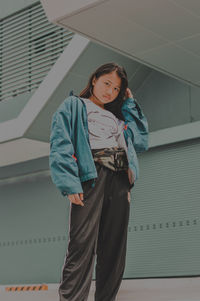 Portrait of young woman standing against wall