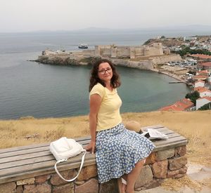 Portrait of woman sitting against sea