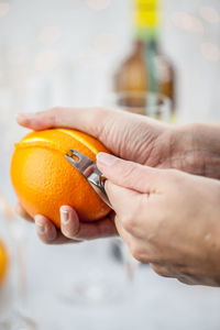 Cropped image of hands peeling orange fruit