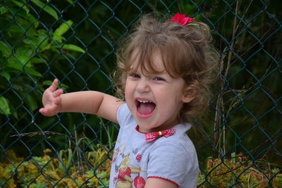 Portrait of cute girl standing against chainlink fence