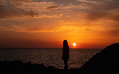 Silhouette man standing on beach against sky during sunset