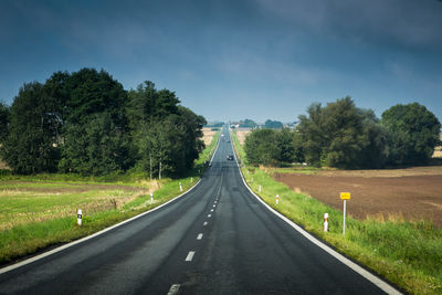 Empty road amidst trees against sky