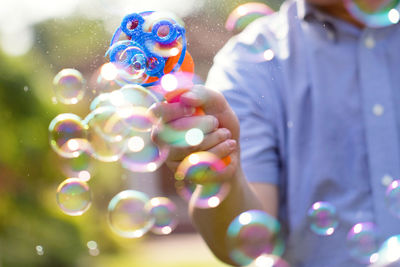 Midsection of man playing with bubble gun