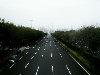 Cars on highway amidst trees against sky