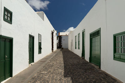 Empty alley amidst buildings against sky