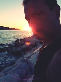 Close-up of man in sea against sunset sky