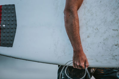 Midsection of man holding surfboard