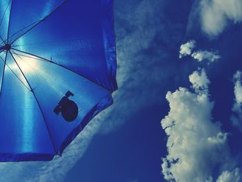 Low angle view of lighting equipment hanging against blue sky