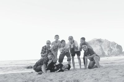 People sitting on beach against clear sky