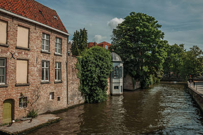 Canal amidst trees and buildings against sky