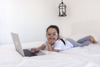 Young woman using laptop while sitting on bed at home
