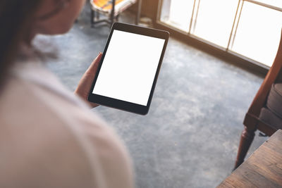 Midsection of woman holding digital tablet while sitting at cafe