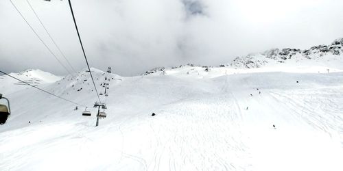 Overhead cable cars over snow covered mountains against sky