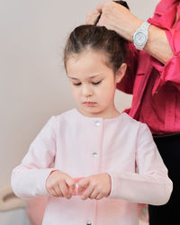 Expressive little girl being dressed by grandmother