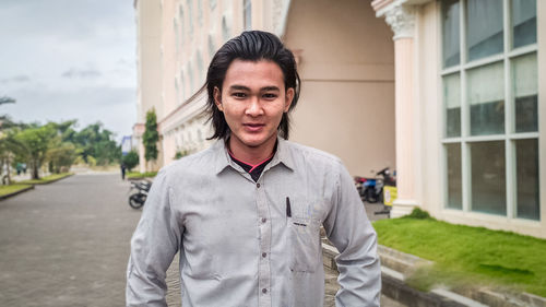 Portrait of young man standing on street in city