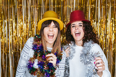 Portrait of smiling friends wearing hat while standing against tinsels