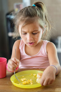 Little girl eating in the kitchen making a dissapointed face