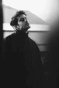 Thoughtful young man looking away while standing in balcony