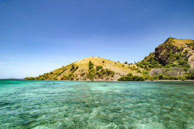 Scenic view of sea and mountains against clear blue sky