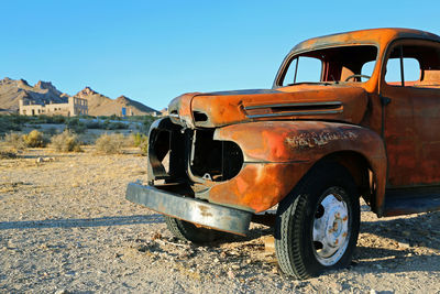 Abandoned vintage car against clear blue sky
