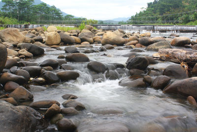 Scenic view of pebbles in river against sky