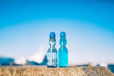 Close-up of glass bottle against blue sky