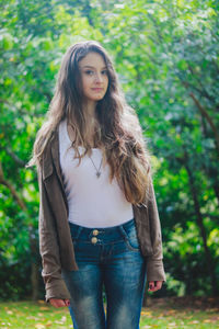 Portrait of smiling young woman standing against trees