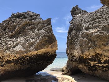 Rock formations on beach against sky