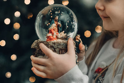 Girl looking at a glass ball with a scene of the nativity of jesus christ in a glass