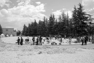 People by trees against sky