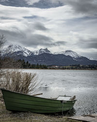 Boat moored in lake against sky during winter