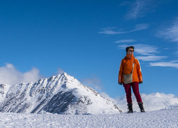 Woman standing on snow covered mountain against sky