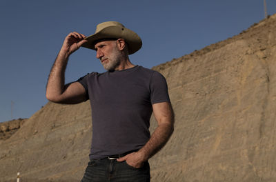 Adult man in cowboy on desert against mountain. almeria, spain