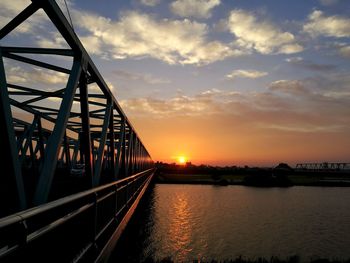 Bridge over river against sky during sunset
