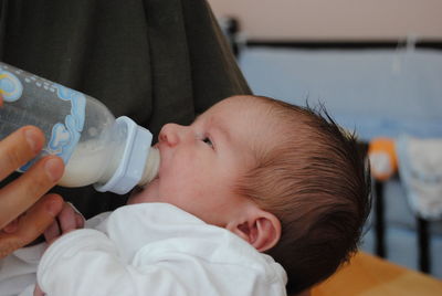 Midsection of mother feeding baby at home