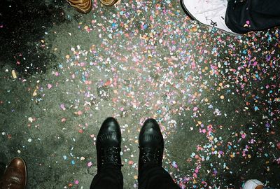 Staring down at shoes on a party floor full of confetti